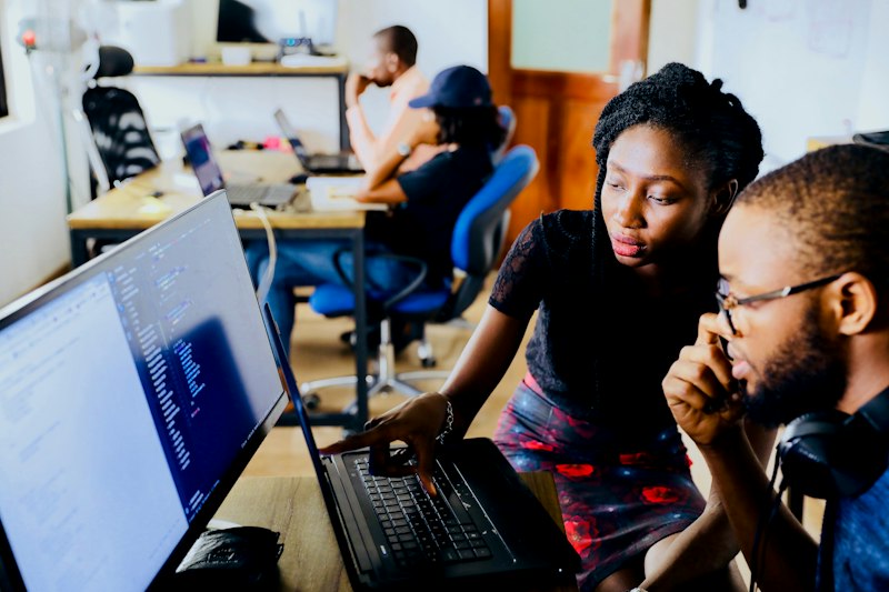 Black software engineers collaborating on code in an office