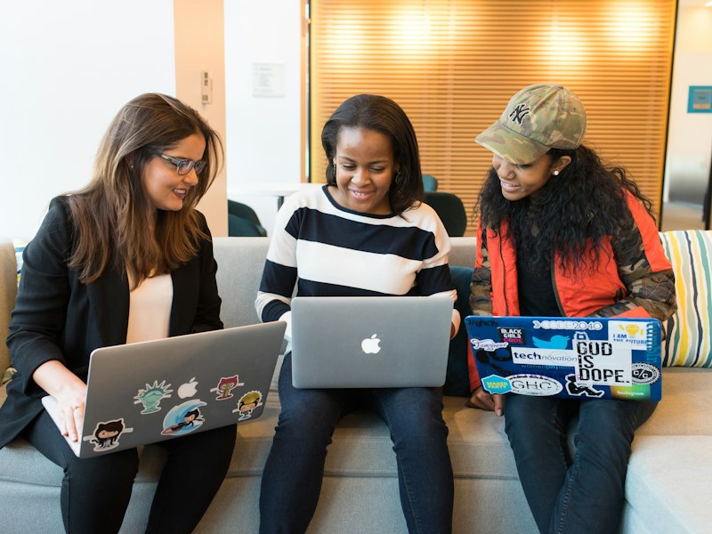 Black women engineers collaborating on laptops in an office